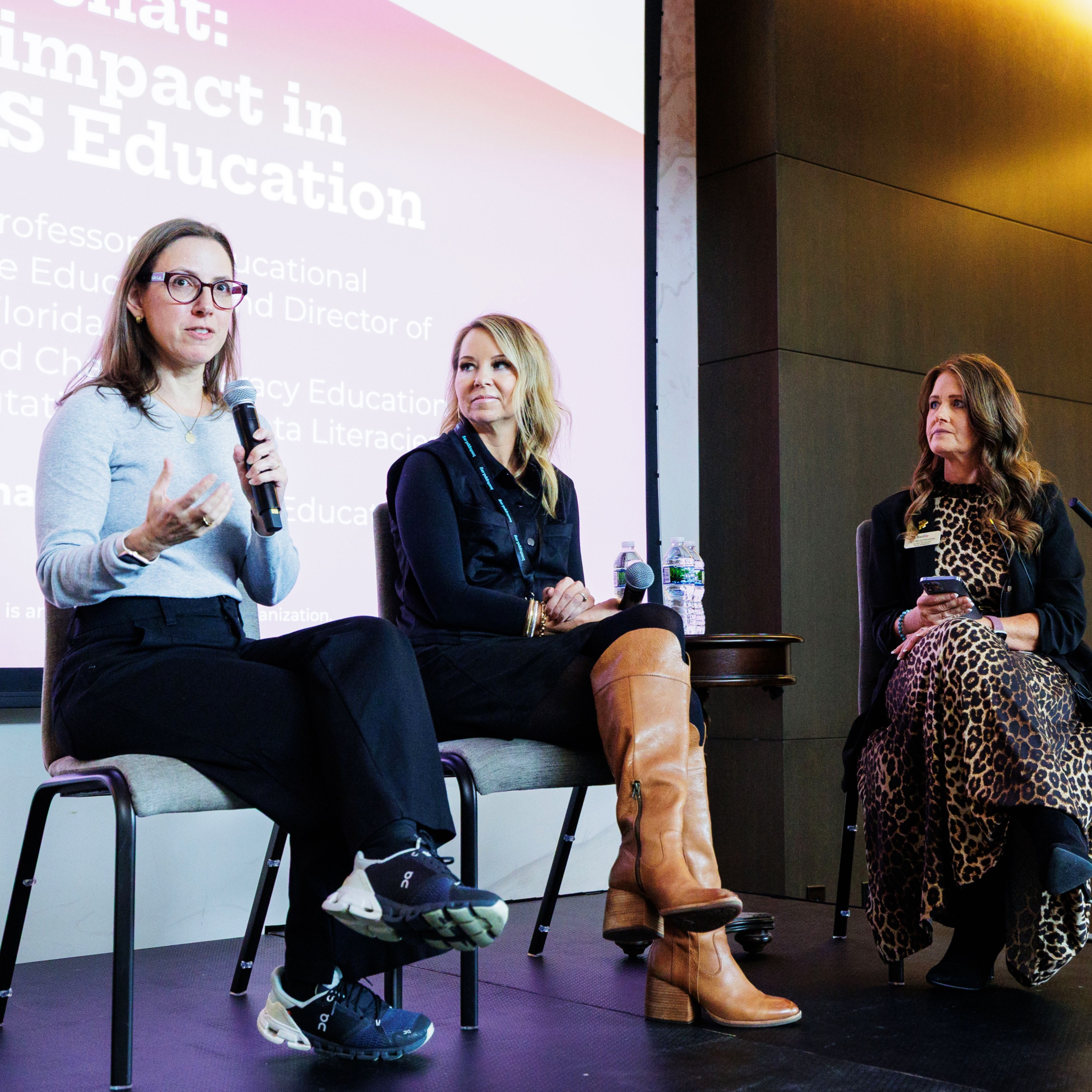 Dr. Maya Israel, Dr. Amy Hutchison , and Dr. Heather Cunningham sit on a stage while speaking at a Measuring Impact in Elementary CS Education panel.